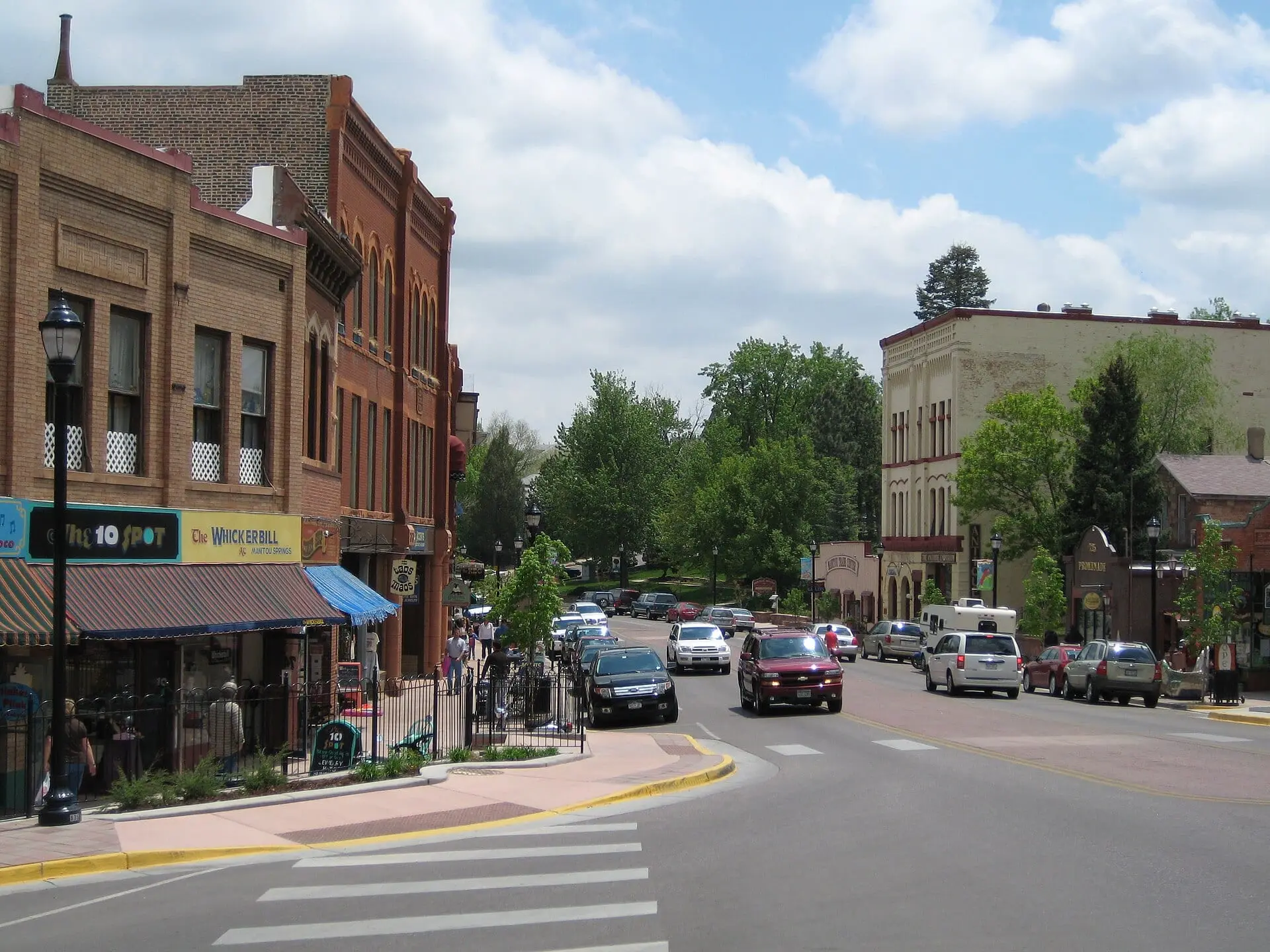 Manitou Avenue in Manitou Springs: brick storefronts on the left and traffic heading down the tree-lined street